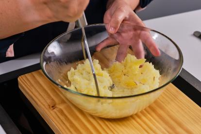 Pelar las patatas y machacar en un bol