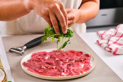 Disponer rúcula fresca encima de la carne