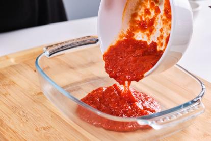 Añadir tomate frito a una bandeja de horno