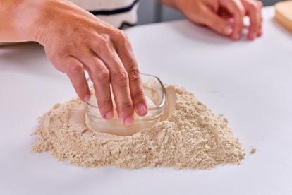 Disponer la harina sobre la encimera y hacer un hueco en el centro