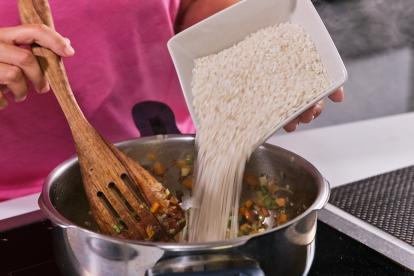 Añadir el arroz midiendo el volumen y rehogarlo con las verduras