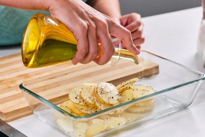 Sazonar las patatas y regar con aceite de oliva