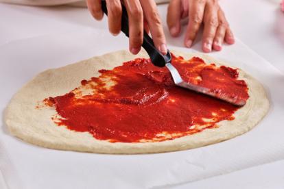 Repartir el tomate por la base de pizza