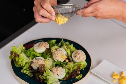 Sobre un lecho de hojas de ensalada colocar los huevos rellenos y espolvorear con yema cocida