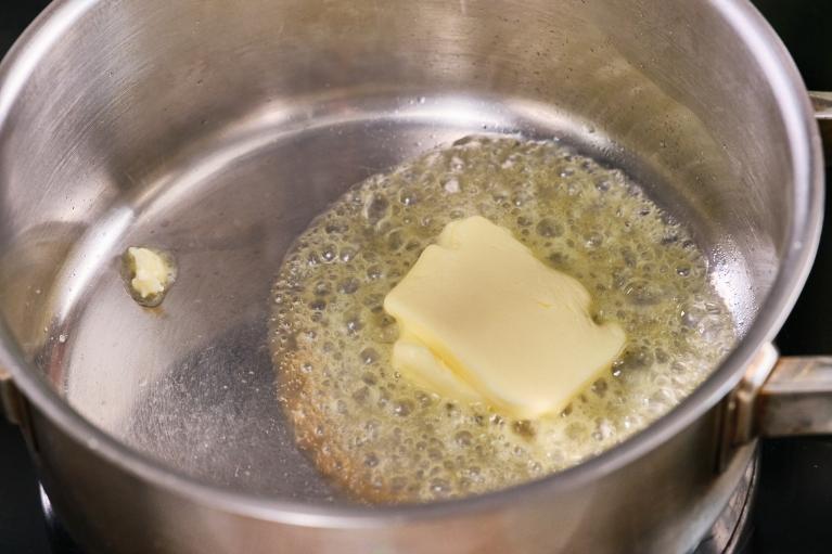 Añadir mantequilla a un cazo al fuego