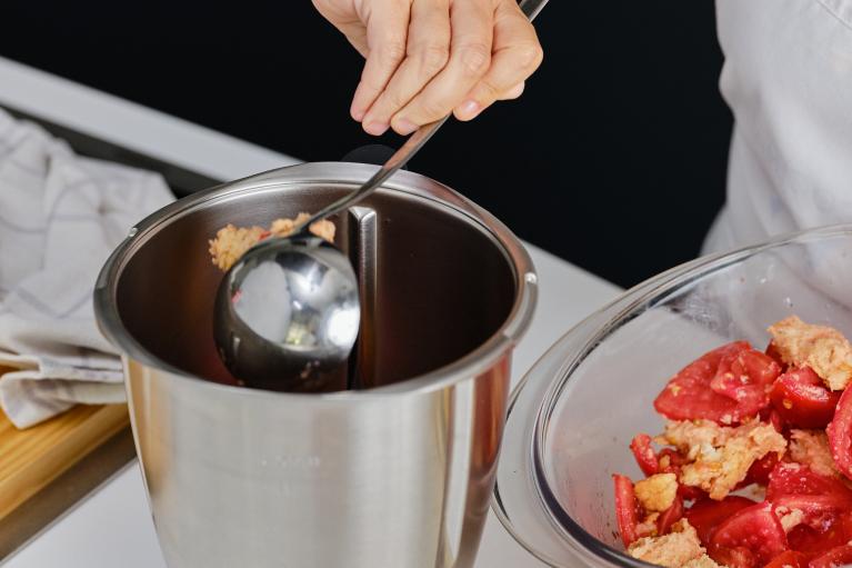 Preparar un vaso triturador y rellenar con un cucharón con la mezcla de tomate y pan