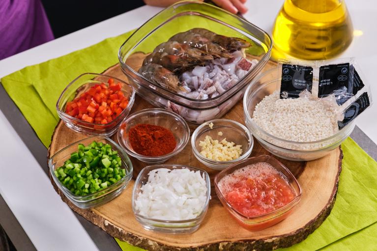 Picar las verduras: cebolla, pimiento rojo, pimiento verde, tomate y ajo. Medir el arroz. Limpiar el calamar y trocear.