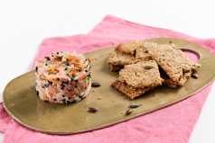 Presentación de tartar de salmón con crackers de semillas.
